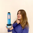 Cargar imagen en el visor de la galería, Chica con mechas sujetando kit DREAM IN COLOR con la mascarilla THE GLAM MASK y el champu COLOR BREEZE SHAMPOO mirando hacia arriba con el dedo en los labios en pose de pensar