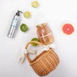 Cargar imagen en el visor de la galería, Bote de mascarilla sin aclarado TROPICAL LEAVE IN rodeado de una cesta, limas, pomelo y un bote de miel