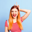 Cargar imagen en el visor de la galería, Chica con tinte naranja balayage con pelo liso alisado haciendo una mueca guiñando un ojo y sacando la lengua