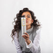 Cargar imagen en el visor de la galería, Chica morena con pelo ondulado sujetando bote de champu anticaspa YOUR BALANCE SHAMPOO mientras lo mira