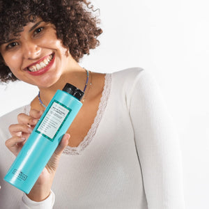 Chica con pelo rizado estilo afro oscuro con champu marino MARINE PLASMA SHAMPOO sonriendo con pintalabios rojo